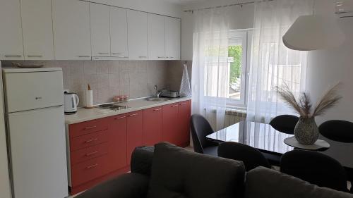 a kitchen with red cabinets and a table with chairs at Lovely Private Flats FREE parking in Novi Sad