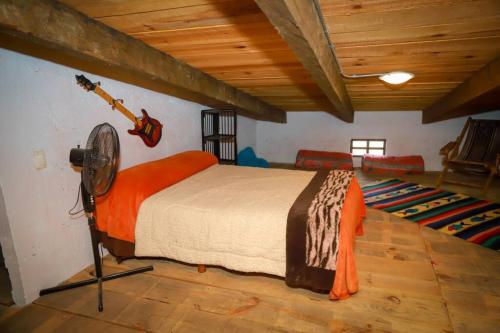 ein Schlafzimmer mit einem Bett mit einem Ventilator und einer Gitarre an der Wand in der Unterkunft Hacienda Cariño de la Montaña 3000 m2 exclusivos in Tlahuapan