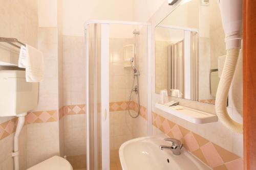 uma casa de banho com um chuveiro, um lavatório e um WC. em Hotel Carnaby em Rimini