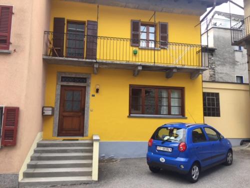 a small blue car parked in front of a yellow house at Verzaschina in Gordola