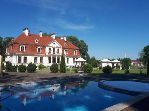 uma casa grande com uma piscina em frente em Sventes Muiža em Svente