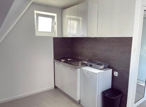 a small kitchen with white cabinets and a sink at Apartmani Agi in Budva