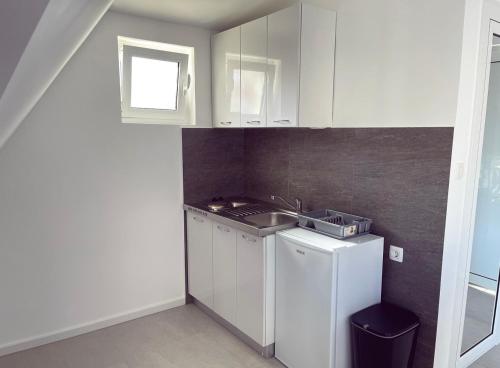 eine kleine Küche mit weißen Schränken und einem Waschbecken in der Unterkunft Apartmani Agi in Budva