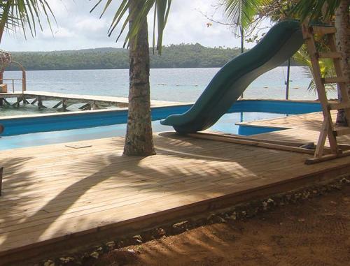 a playground with a slide next to the water at Tongan Beach Resort in Utungake