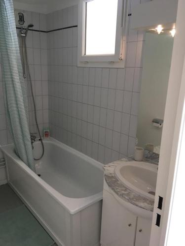 une salle de bain blanche avec une baignoire et un lavabo dans l'établissement Studio très bien situé, belle vue, parking privé, à Bagnères-de-Bigorre