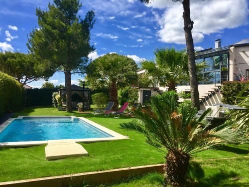 a garden with a swimming pool and palm trees at L'ESCALE COTE BLEUE B&B AND Spa in Sausset-les-Pins