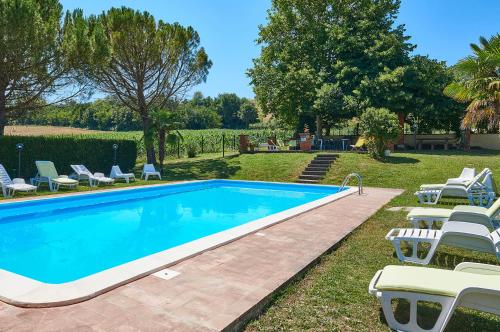 a swimming pool with lounge chairs next to a yard at La Rosa in Città di Castello