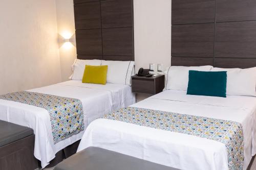 two beds sitting next to each other in a room at Hotel Expo Abastos in Guadalajara