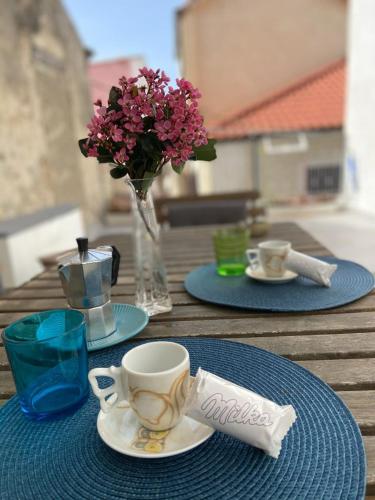 a table with two plates and a cup and a vase with flowers at Il Casalino Apartment in Pizzo