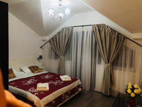 a bedroom with a bed and curtains and a chandelier at Perla Muntilor Ponoarele, Padurea de liliac in Ponoarele
