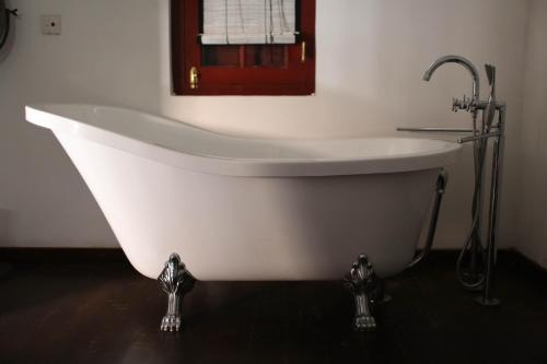 a white bath tub in a bathroom with a window at Royal Bar & Hotel in Kandy