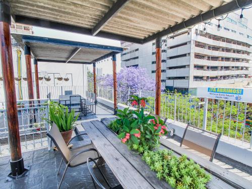 eine Terrasse mit einem Holztisch, Stühlen und Pflanzen in der Unterkunft VL Hotel Boutique by Rotamundos in Guadalajara