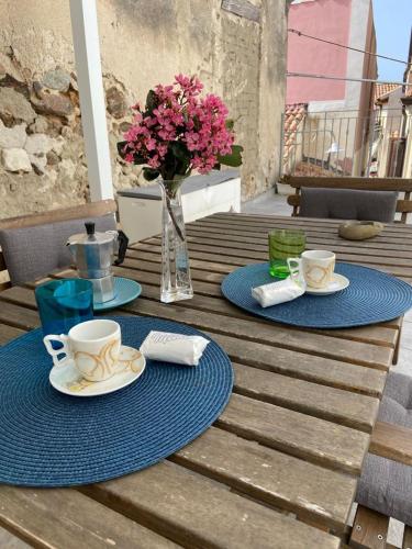 a wooden table with two plates and cups and a vase with flowers at Il Casalino Apartment in Pizzo