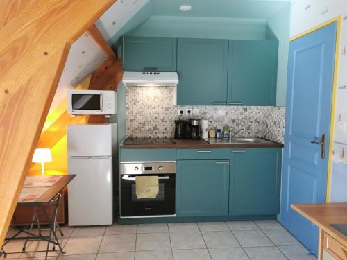 La cuisine est équipée de placards bleus et d'un réfrigérateur blanc. dans l'établissement 3 Chambres-Disneyland Paris, à Saint-Thibault-des-Vignes