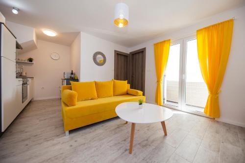 ein Wohnzimmer mit einem gelben Sofa und einem Tisch in der Unterkunft Apartments Haluga in Pag