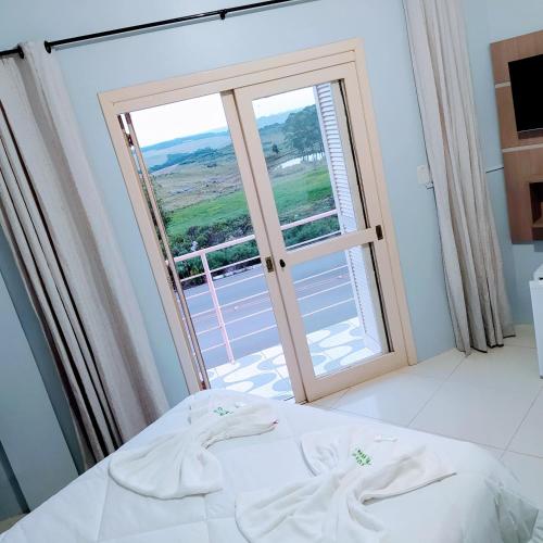 a bedroom with a bed and a large window at Pousada Aparados in Cambará