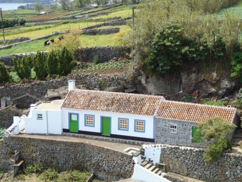a small house with green doors and a stone wall at Casa da Fonte in Angra do Heroísmo