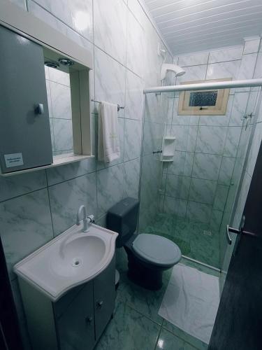 a bathroom with a shower and a toilet and a sink at Pousada Aparados in Cambará