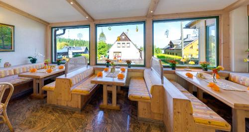 a restaurant with benches and tables and large windows at Ferienhotel Mühlleithen in Klingenthal