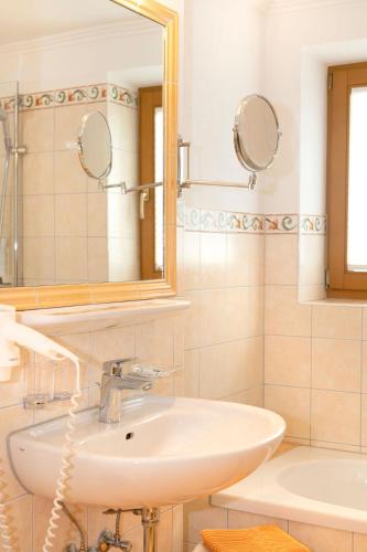 a bathroom with a sink and a mirror at Hotel Schneeberger in Niederau