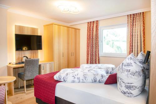 a hotel room with a bed and a desk at Hotel Schneeberger in Niederau