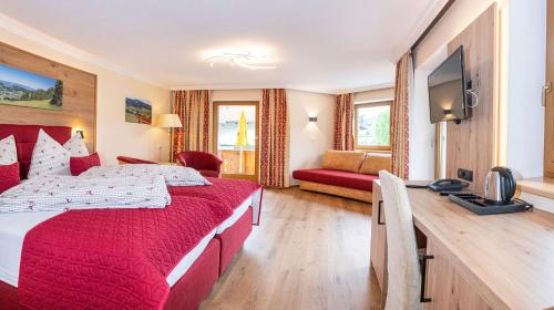 a hotel room with a red bed and a television at Hotel Schneeberger in Niederau