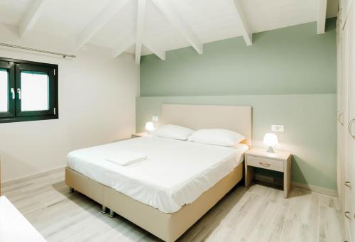 een witte slaapkamer met een wit bed en een raam bij Tommys House in Parga