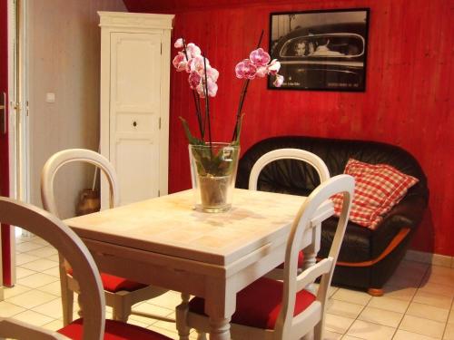 una mesa de comedor con un jarrón de flores. en Gite les Orchidées, en Honfleur