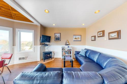 Una sala de estar con un sofá azul y un televisor. en Berni's Ocean View Castle - The Crow's Nest, en Oceanside