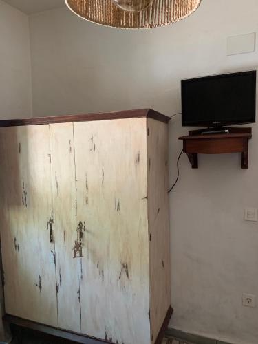 a wooden cabinet with a tv on a wall at Finca Las Fuentezuelas in Carataunas