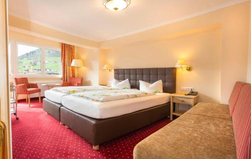 a hotel room with a large bed and a table at Hotel Schneeberger in Niederau