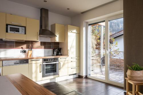 a kitchen with white cabinets and a sliding glass door at Elinas Mountain Views in Kaprun