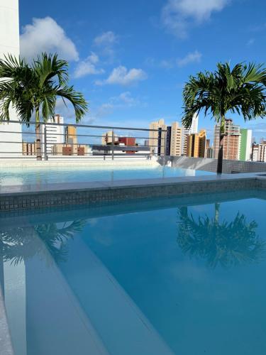 uma piscina com palmeiras e uma cidade ao fundo em Manaíra Apart Hotel em João Pessoa
