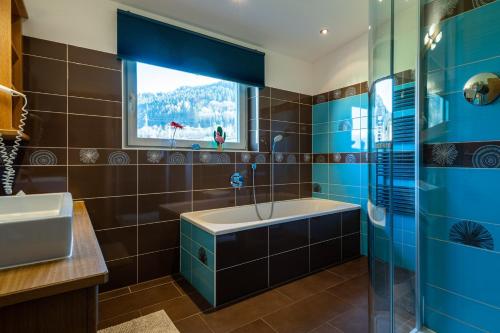 a bathroom with a tub and a sink and a window at Elinas Mountain Views in Kaprun