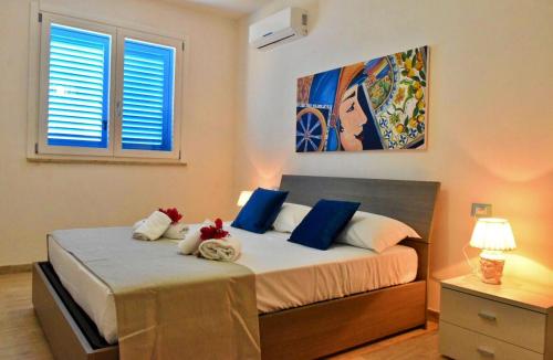 a bedroom with a bed with blue and white pillows at Casa Nettuno Favignana in Favignana