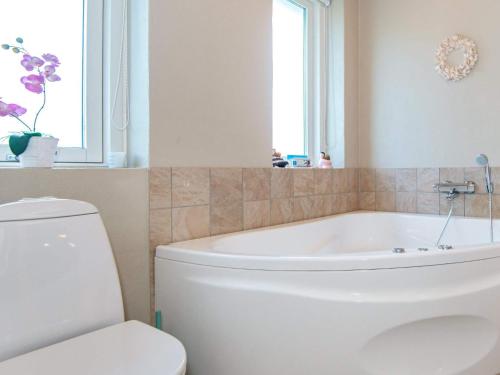 a bathroom with a white tub and a toilet at 12 person holiday home in Aabenraa in Loddenhøj
