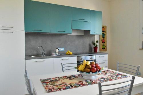 a kitchen with blue cabinets and a table with a bowl of fruit at Casa Nettuno Favignana in Favignana