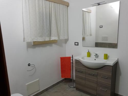une salle de bain blanche avec un lavabo et un miroir dans l'établissement Casa Vacanze Nonna Maria, à Carpignano Salentino