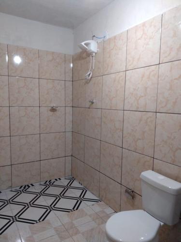 uma casa de banho com WC e piso em azulejo preto e branco em Pousada Vicenzi em Luziânia