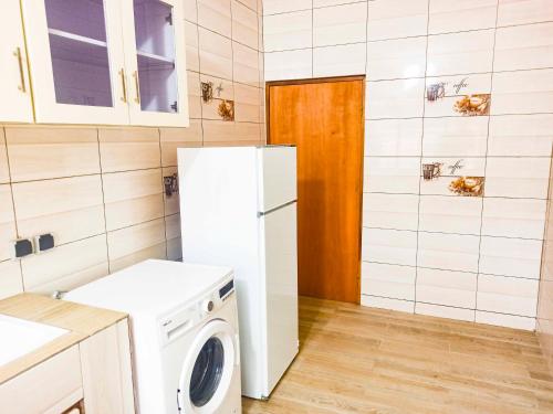 a kitchen with a white refrigerator and a washing machine at Appartement F4 Climatisé niveau Etage à Totsi près de la maison ADEBAYOR in Agbalé Pédo