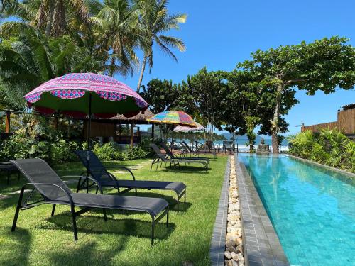 a group of chairs and umbrellas next to a swimming pool at Pousada TeMoana in Ubatuba