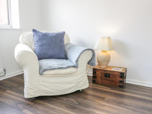 a white chair with a blue pillow sitting next to a lamp at 22 Gwel Yr Wyddfa in Menai Bridge