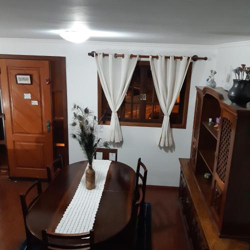 a dining room table with a vase of flowers on it at SILVÉRIOS Suítes DA MONTANHA in Campos do Jordão