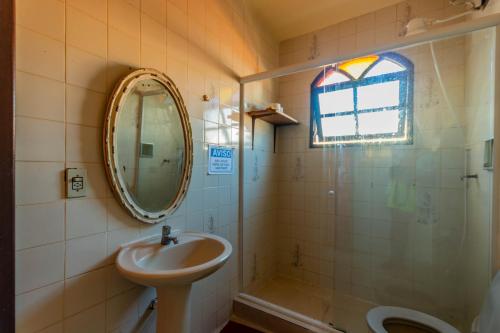 La salle de bains est pourvue d'un lavabo, d'un miroir et d'une douche. dans l'établissement 4 Estações - Arraial, à Arraial do Cabo
