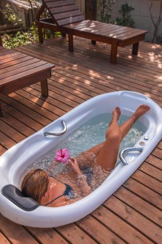 a woman laying in a bath tub on a deck at Hotel Ferrugem Eco Village in Garopaba