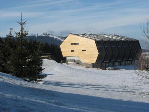 een houten gebouw bovenop een met sneeuw bedekte heuvel bij Apartments Klinovec in Loučná pod Klínovcem