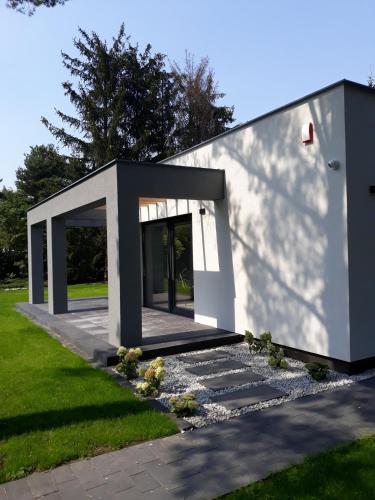 a small white building with a door in a yard at Boszkowo Makowa Cisza in Boszkowo