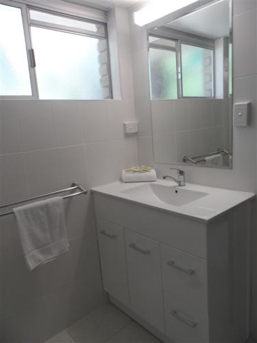 a white bathroom with a sink and a mirror at Arcadia Village Motel in Arcadia