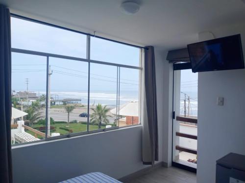 een kamer met een groot raam met uitzicht op de oceaan bij Hospedaje Nuna - Playa Huanchaco in Huanchaco