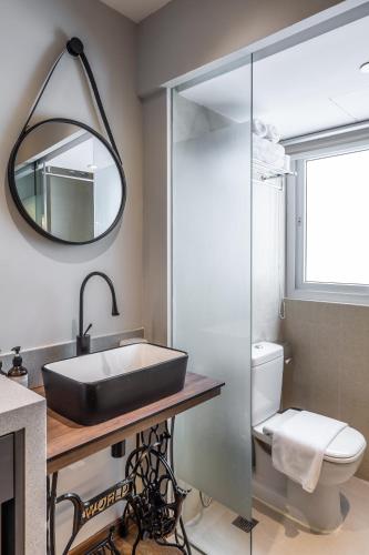 a bathroom with a sink and a toilet and a mirror at Heritage Collection on Seah - Mobile App Check-In in Singapore